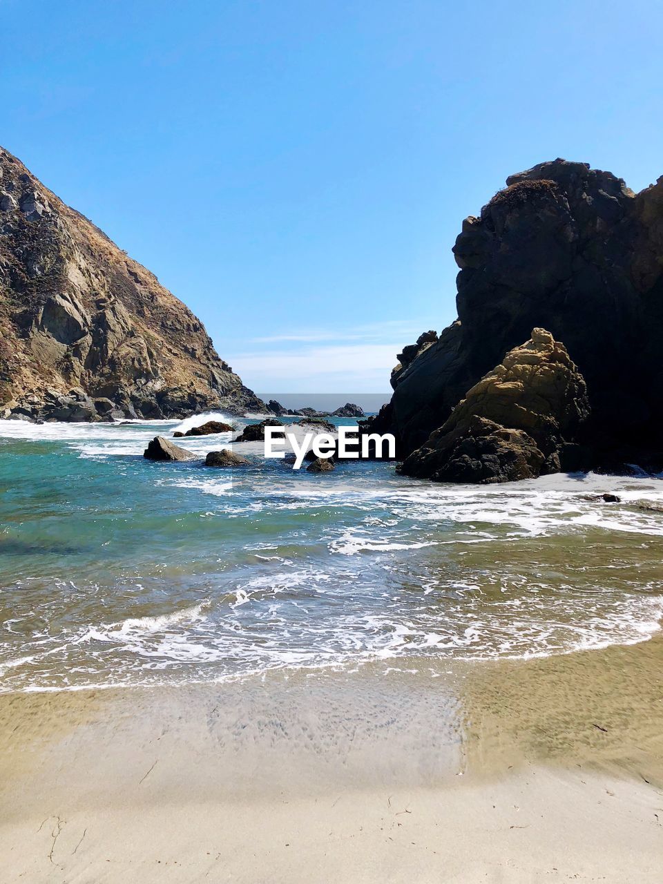 ROCK FORMATION ON BEACH AGAINST SKY