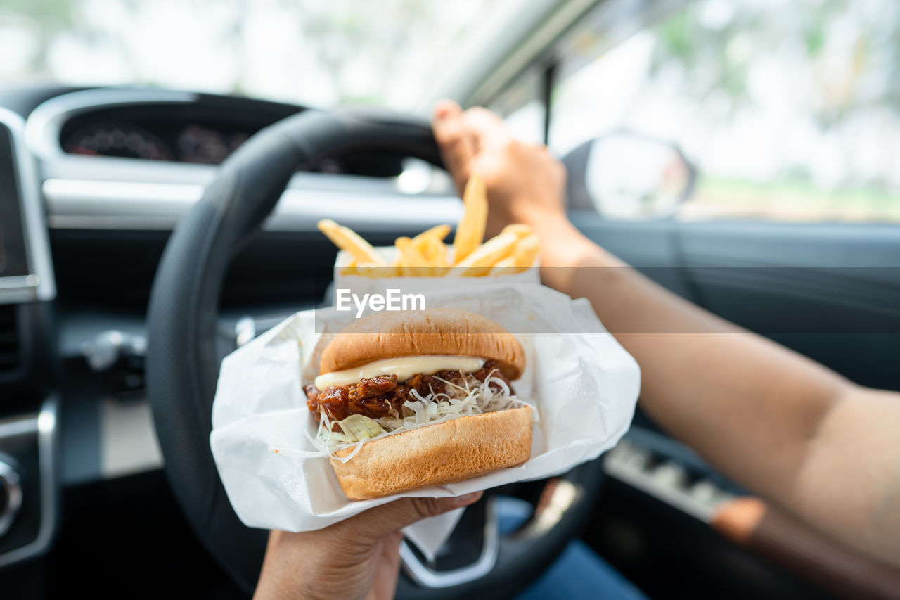 cropped hand of woman holding food in car