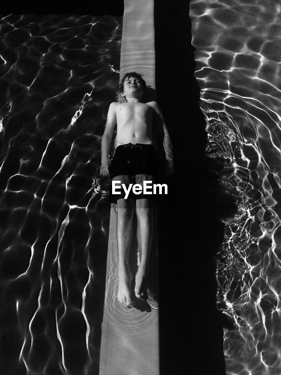 High angle view of boy resting on retaining wall in swimming pool