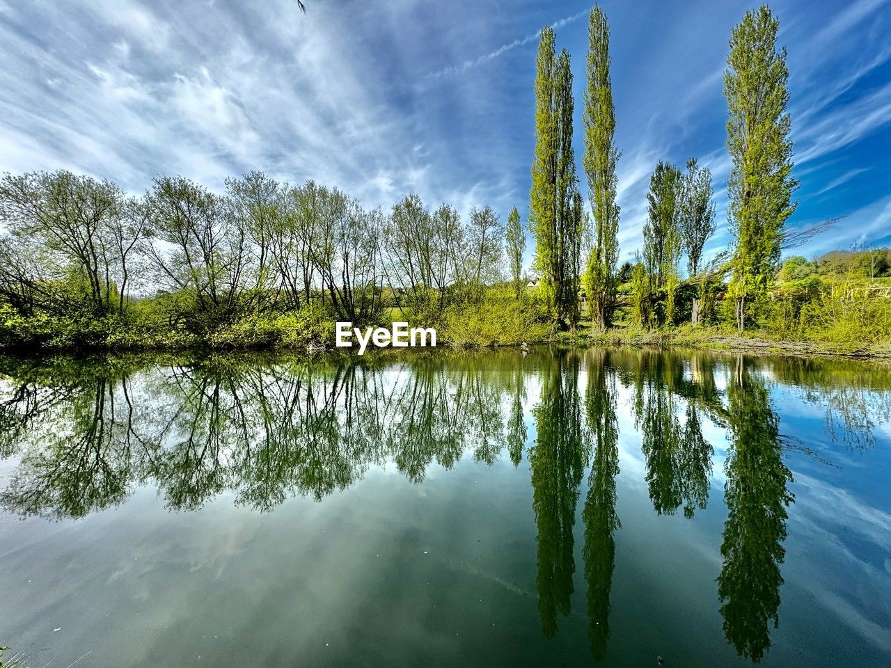 Scenic view of water and tree reflections  against sky during autumn