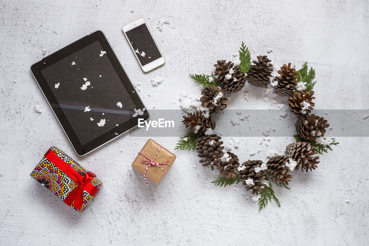 High angle view of christmas decoration and digital tablet by smart phone on table
