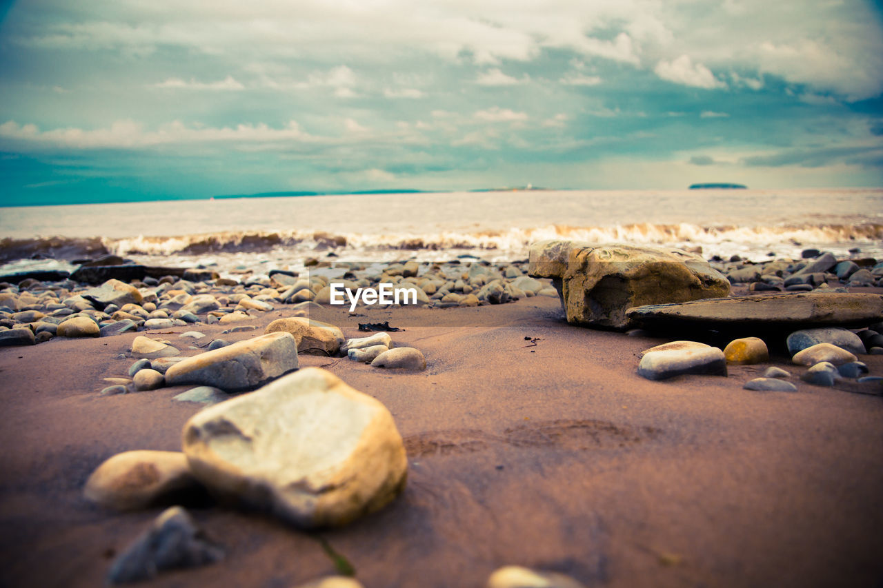 Rocks on shore at beach against sky