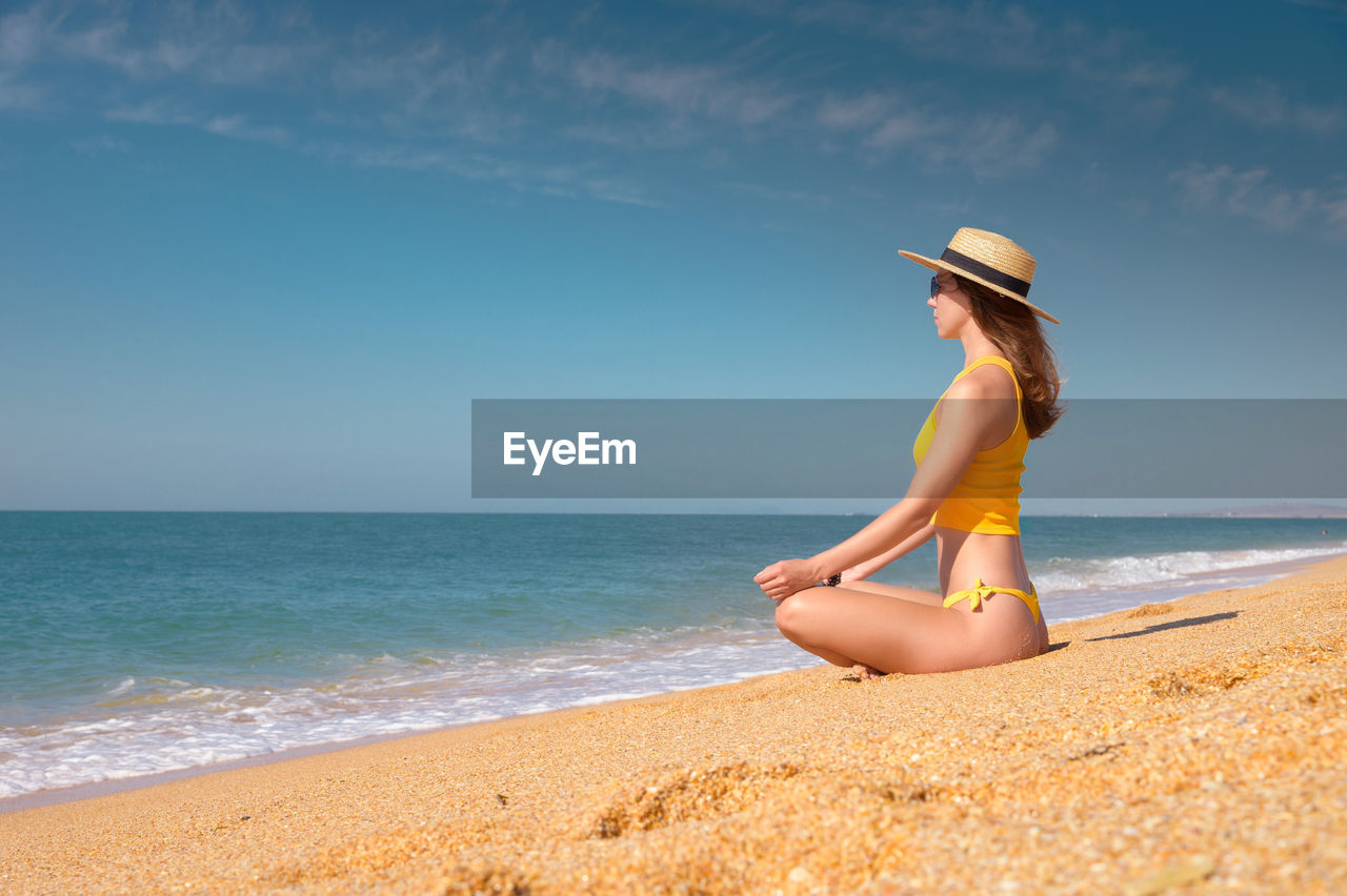 Woman meditating while sitting on beach