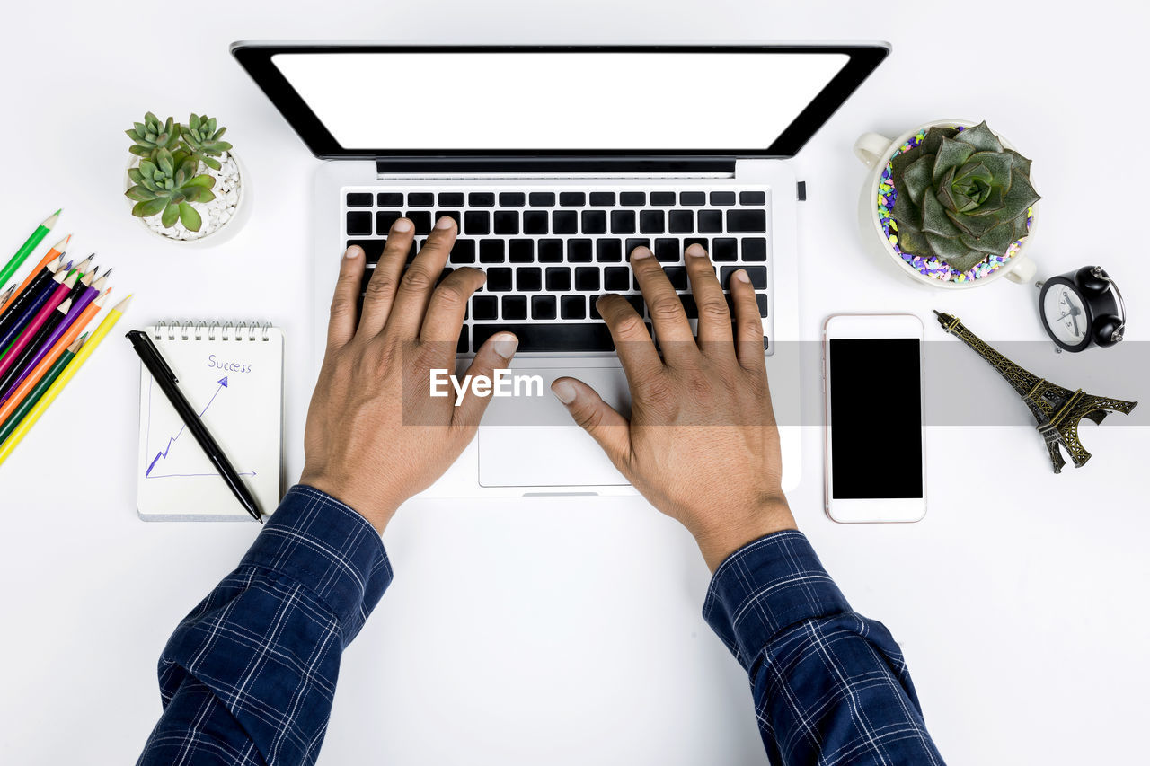 Cropped hands of man using laptop on table