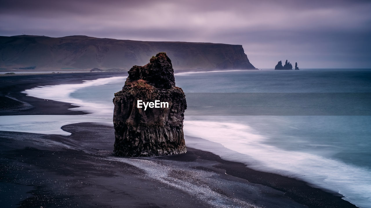 Rock formation by sea against sky during sunset