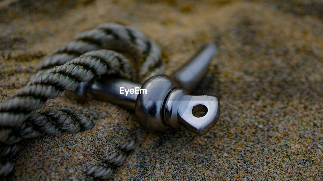 Close-up of rope with metal in sand