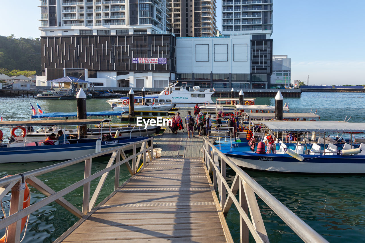 BOATS IN SEA AGAINST MODERN BUILDINGS