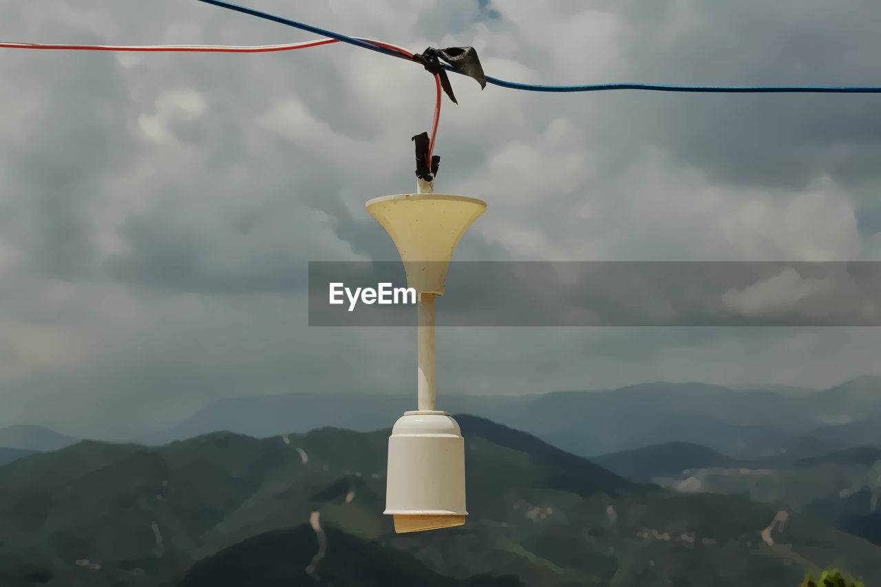 Close-up of light bulb hanging against sky