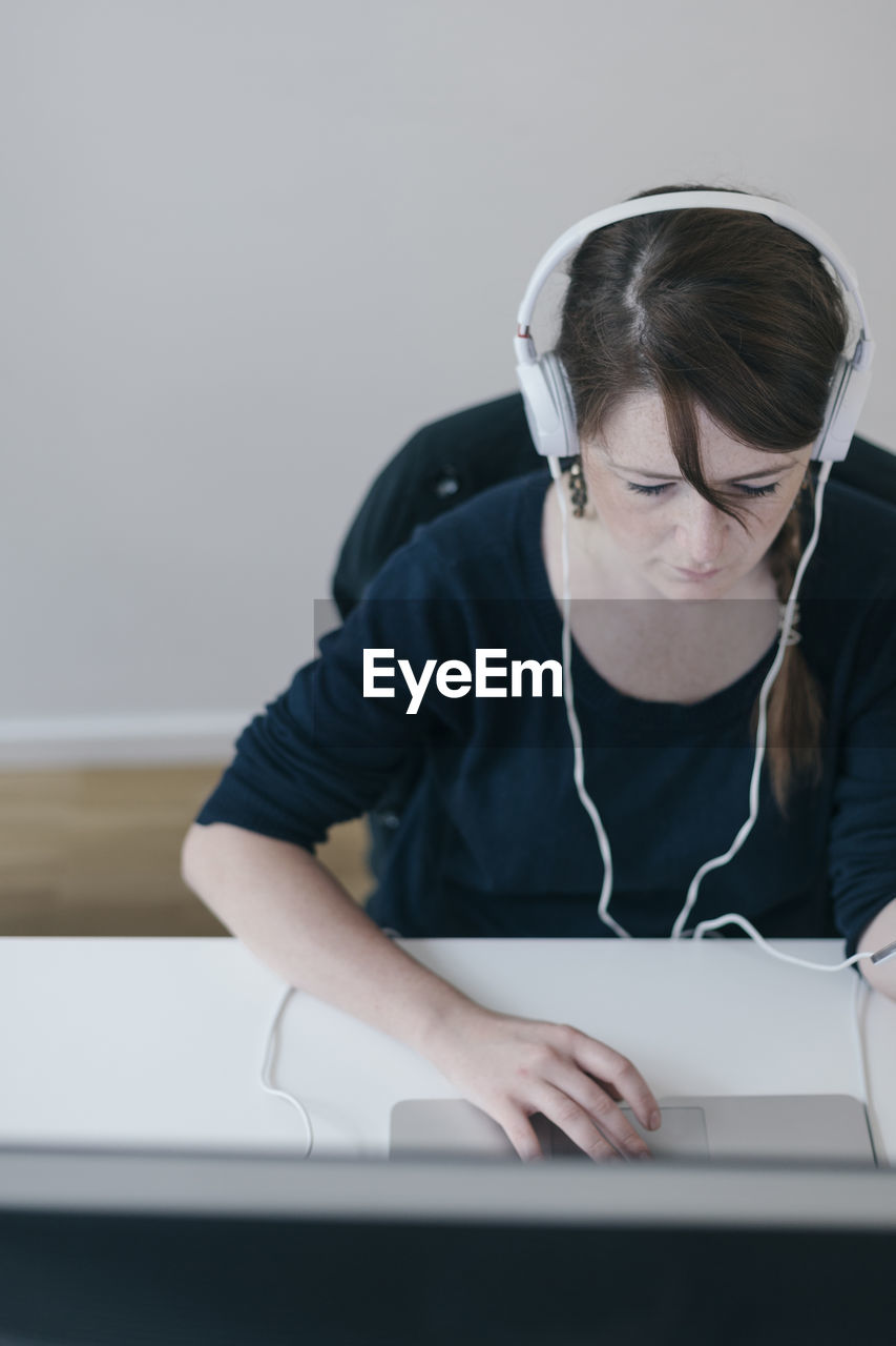 Woman wearing headphones working with computer