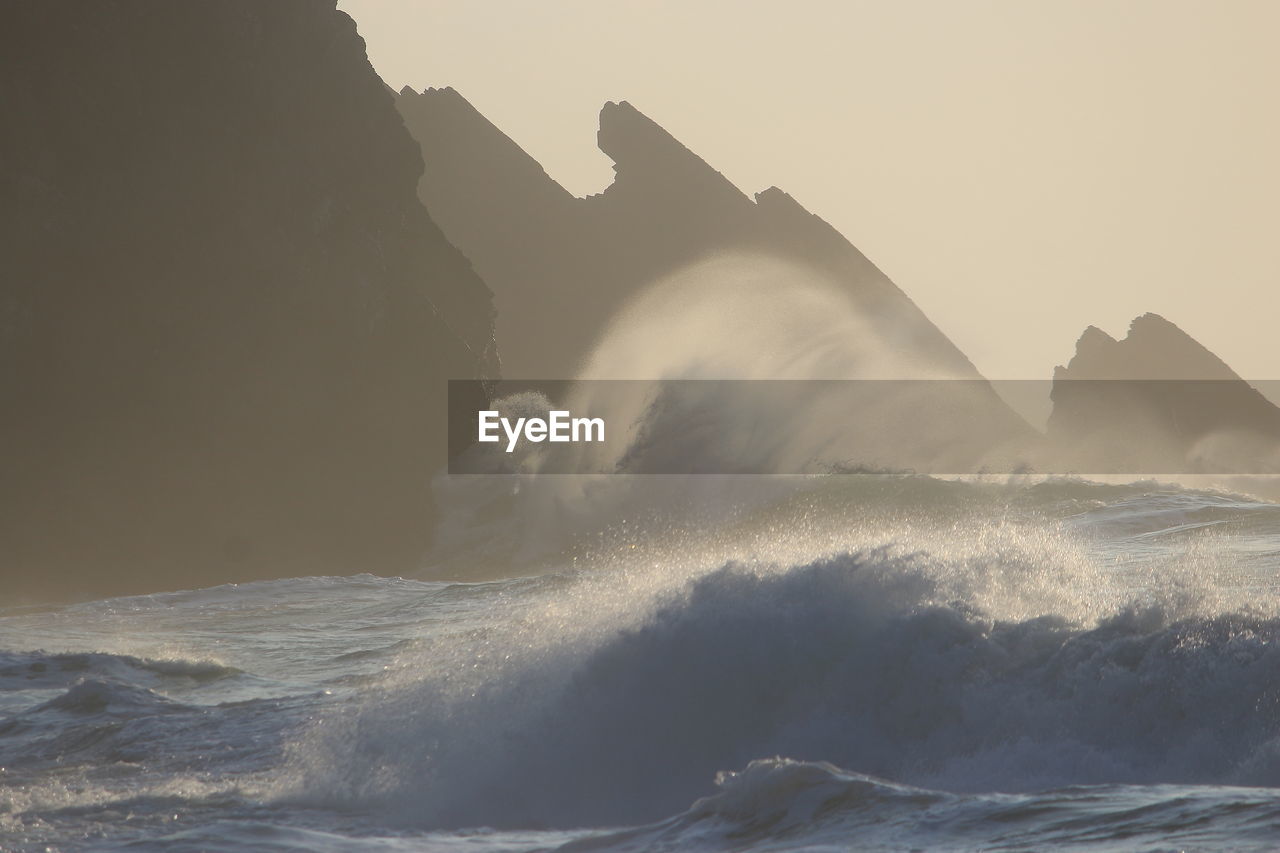 MAN SPLASHING WATER IN SEA AGAINST SKY