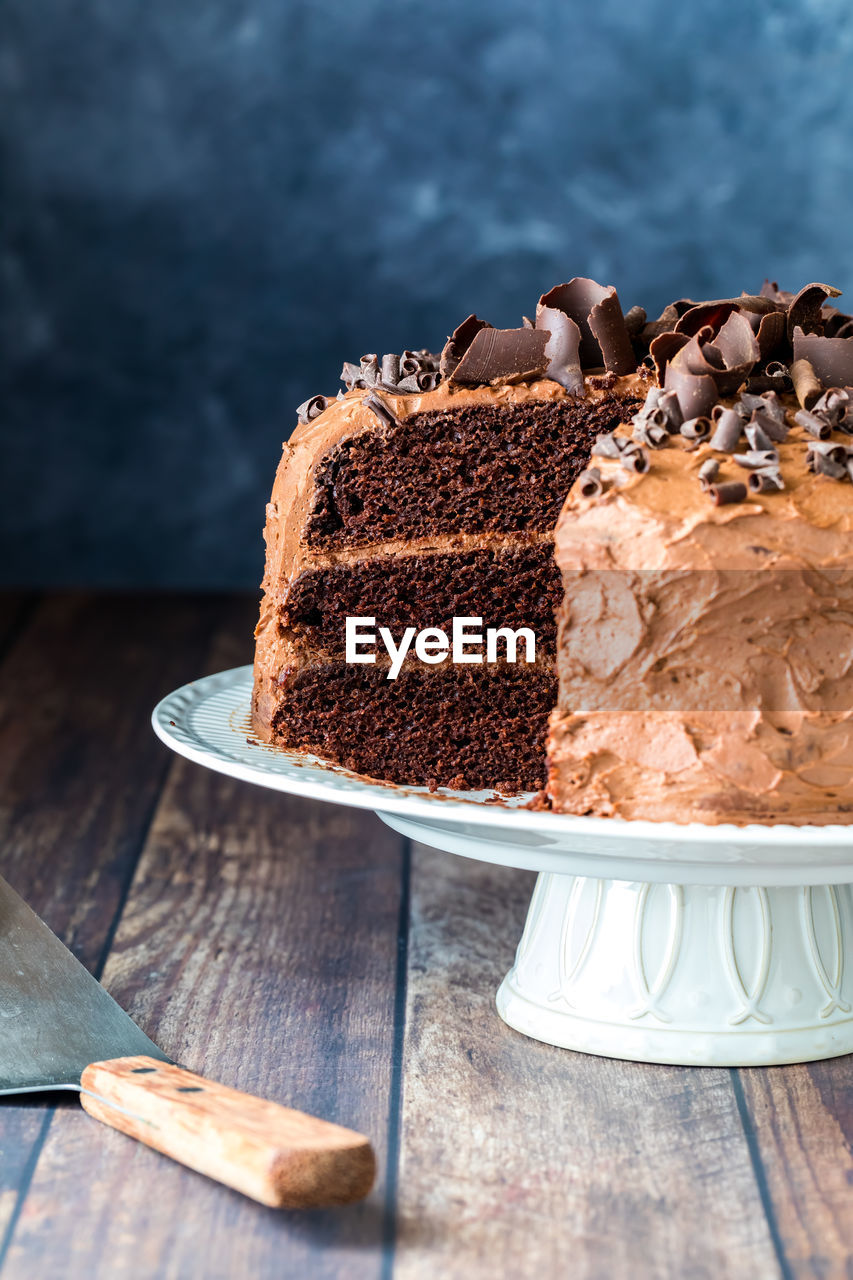 A triple layered decadent low sugar chocolate cake with one slice removed.