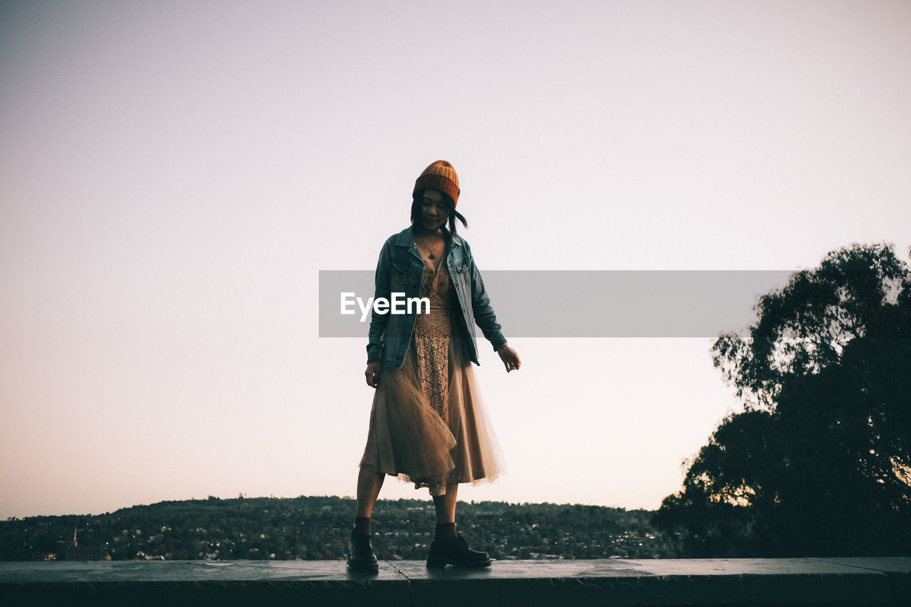 rear view of woman standing on beach against sky during sunset