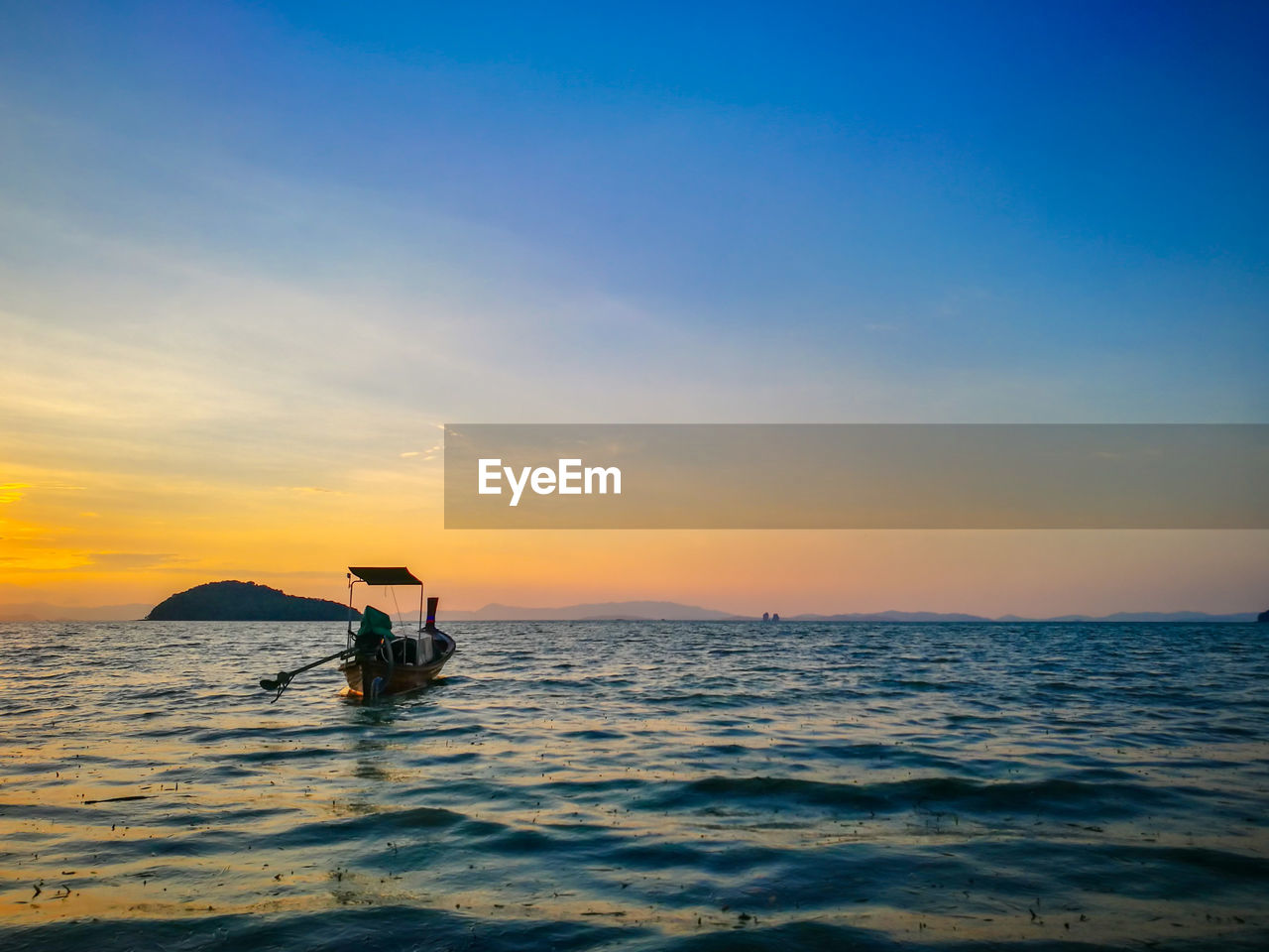 Boat moored in sea against sky during sunset