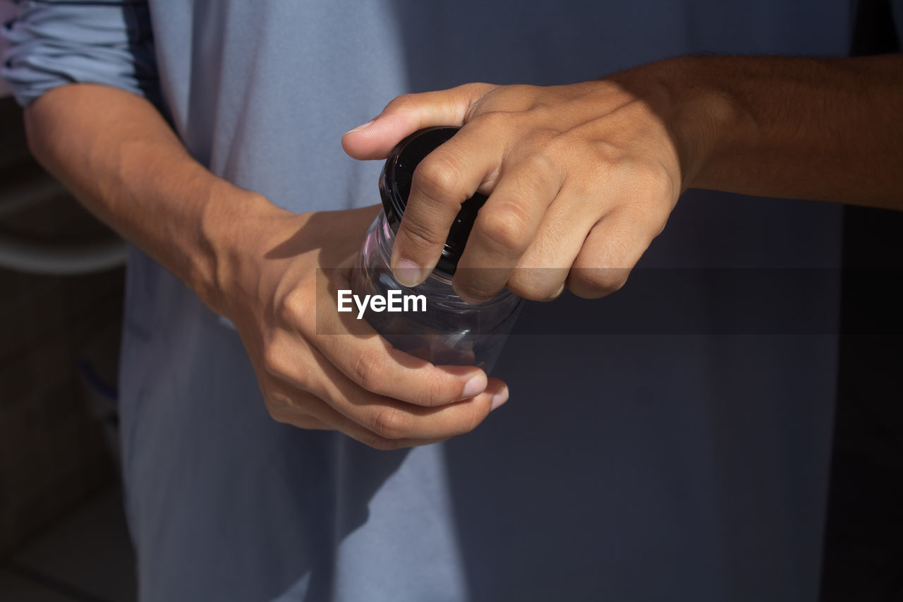 midsection of man holding water bottle