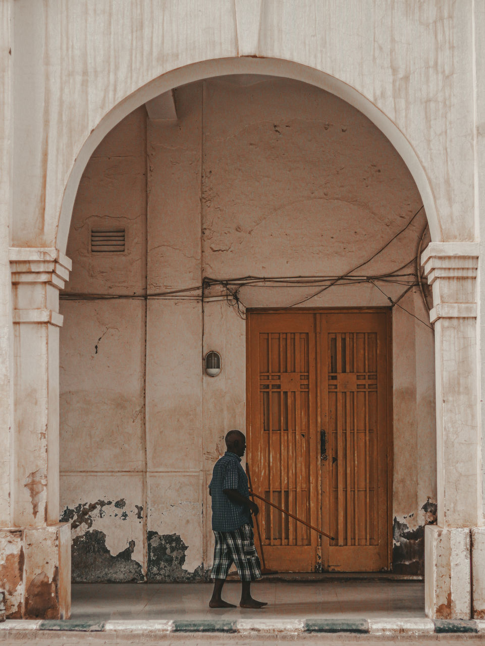 Rear view of man sweep the corridor of an ancient building 