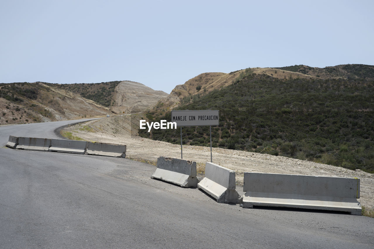 ROAD SIGN ON MOUNTAIN AGAINST CLEAR SKY