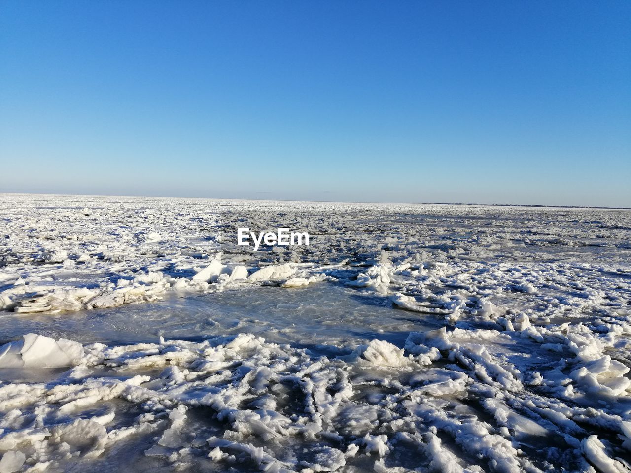 SNOW COVERED SHORE AGAINST CLEAR BLUE SKY