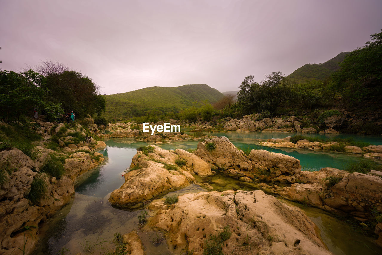 Scenic view of rocks by river against sky