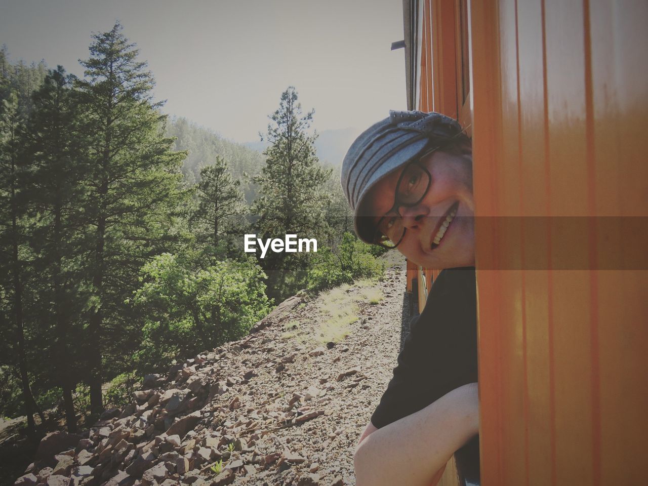 Portrait of smiling woman peeking from train at forest