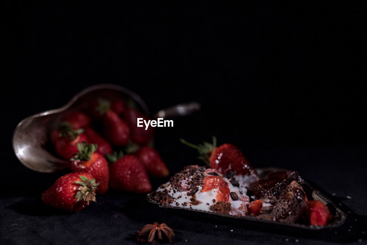 White ice cream with chocolate drops with strawberries on a black background
