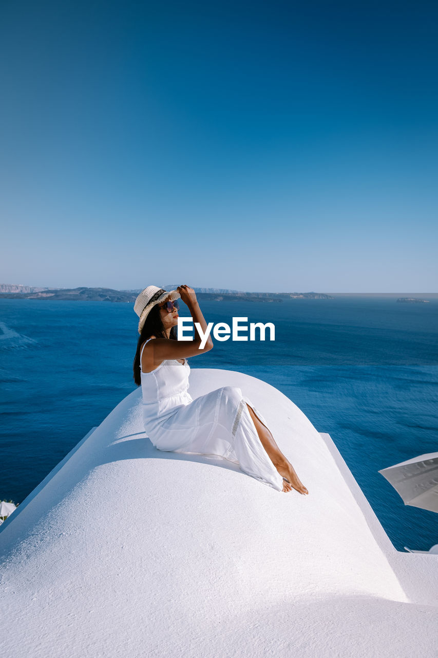 WOMAN ON SWIMMING POOL AGAINST SEA