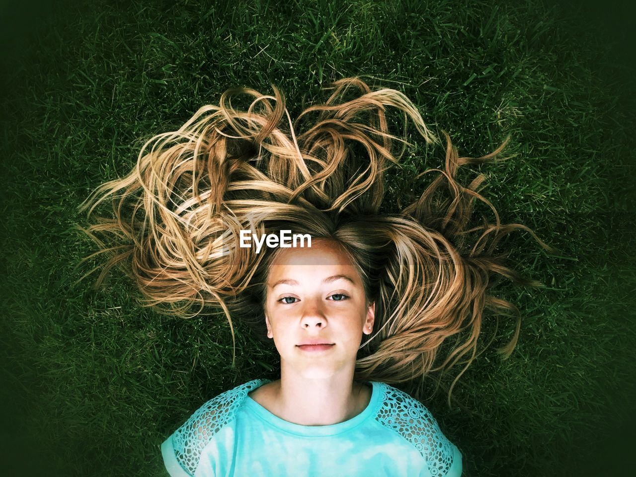 Portrait of young woman lying on grassy field