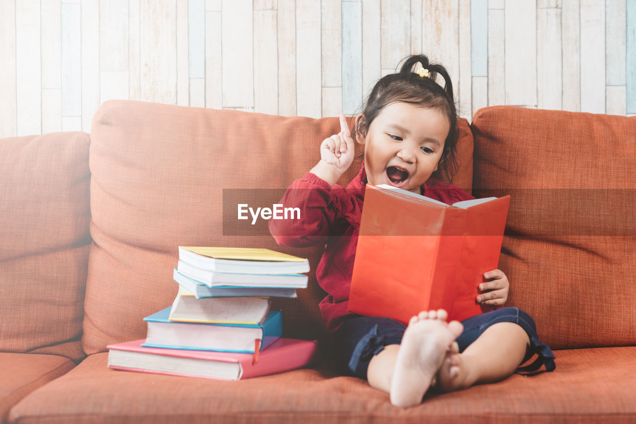 Smiling girl sitting on sofa at home