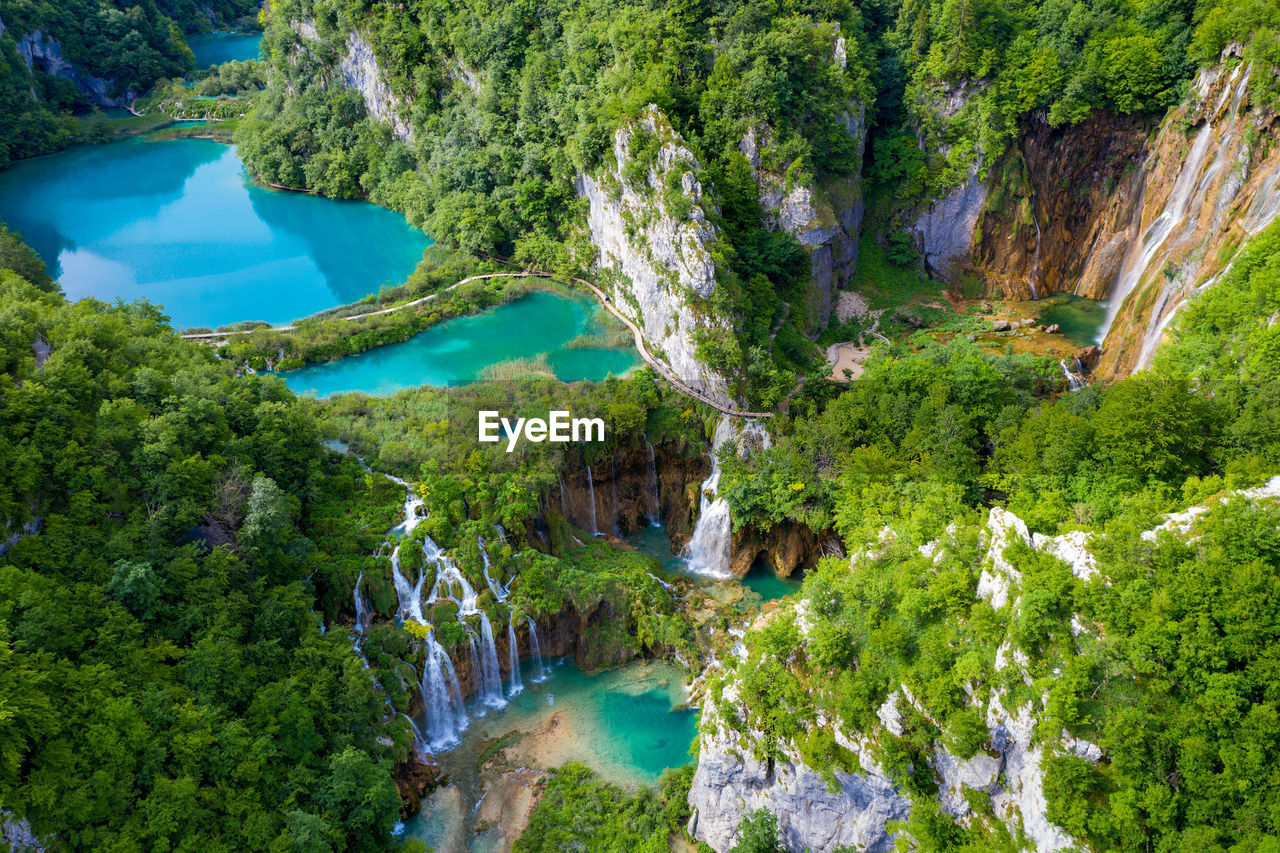 HIGH ANGLE VIEW OF WATERFALL AMIDST TREES