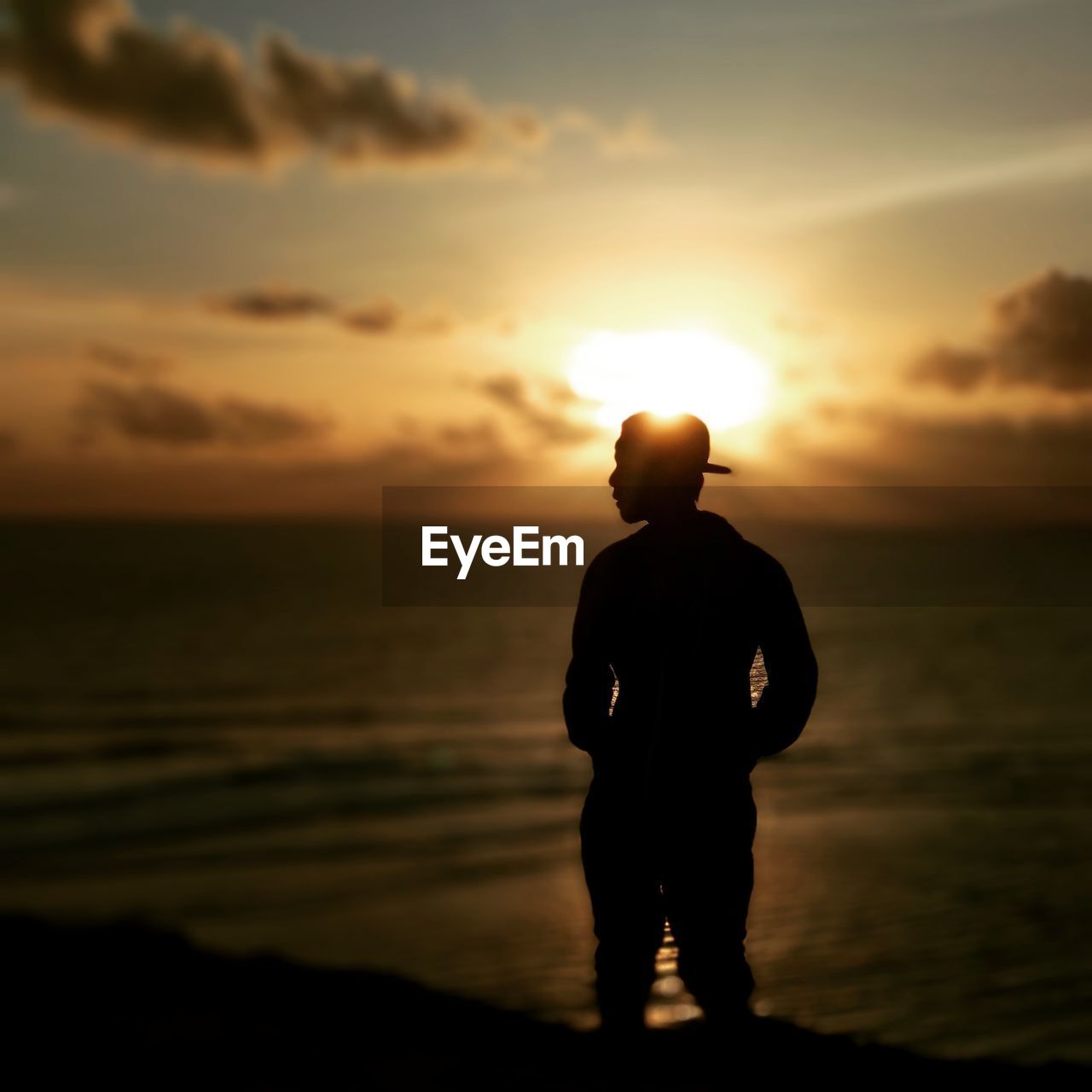 SILHOUETTE MAN STANDING ON BEACH DURING SUNSET