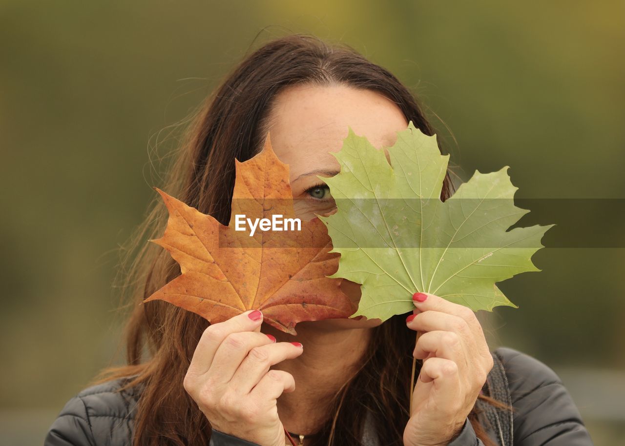 Close-up of woman holding autumn leaves