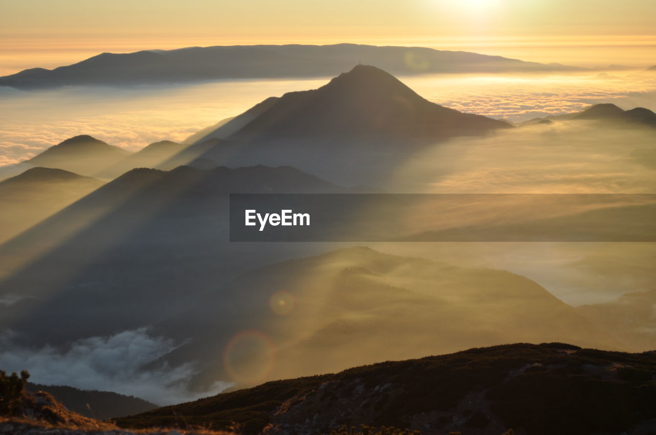 Idyllic shot of mountains in foggy weather during sunrise