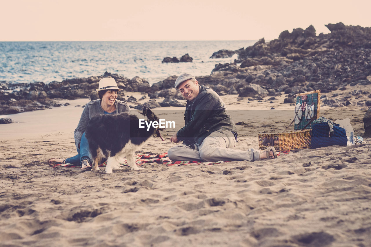 Happy couple sitting with dog at beach