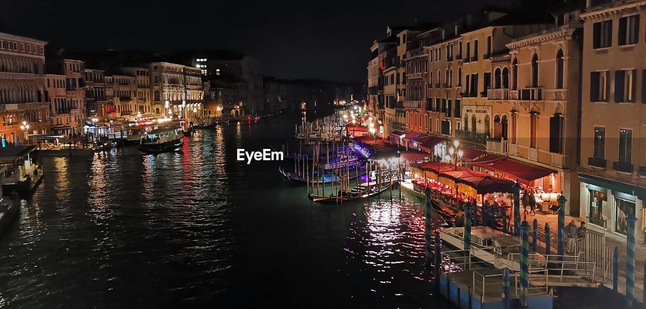 nautical vessel, water, architecture, transportation, building exterior, mode of transportation, canal, night, city, built structure, evening, reflection, travel destinations, cityscape, gondola, illuminated, travel, waterway, tourism, nature, boat, moored, vehicle, building, waterfront, ship, holiday, sky, outdoors, residential district, no people, watercraft, city life, street