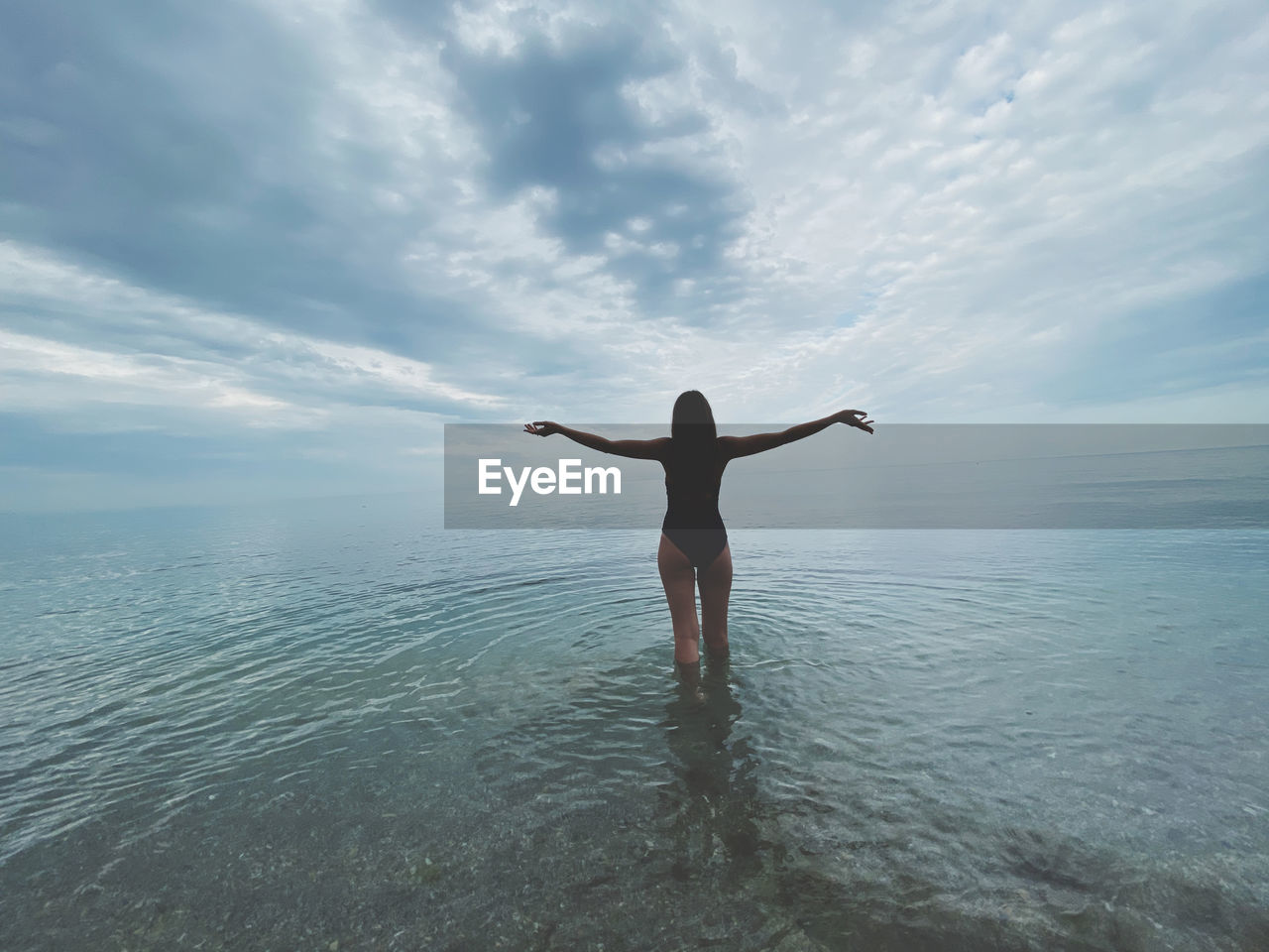 Rear view of women standing in sea against sky