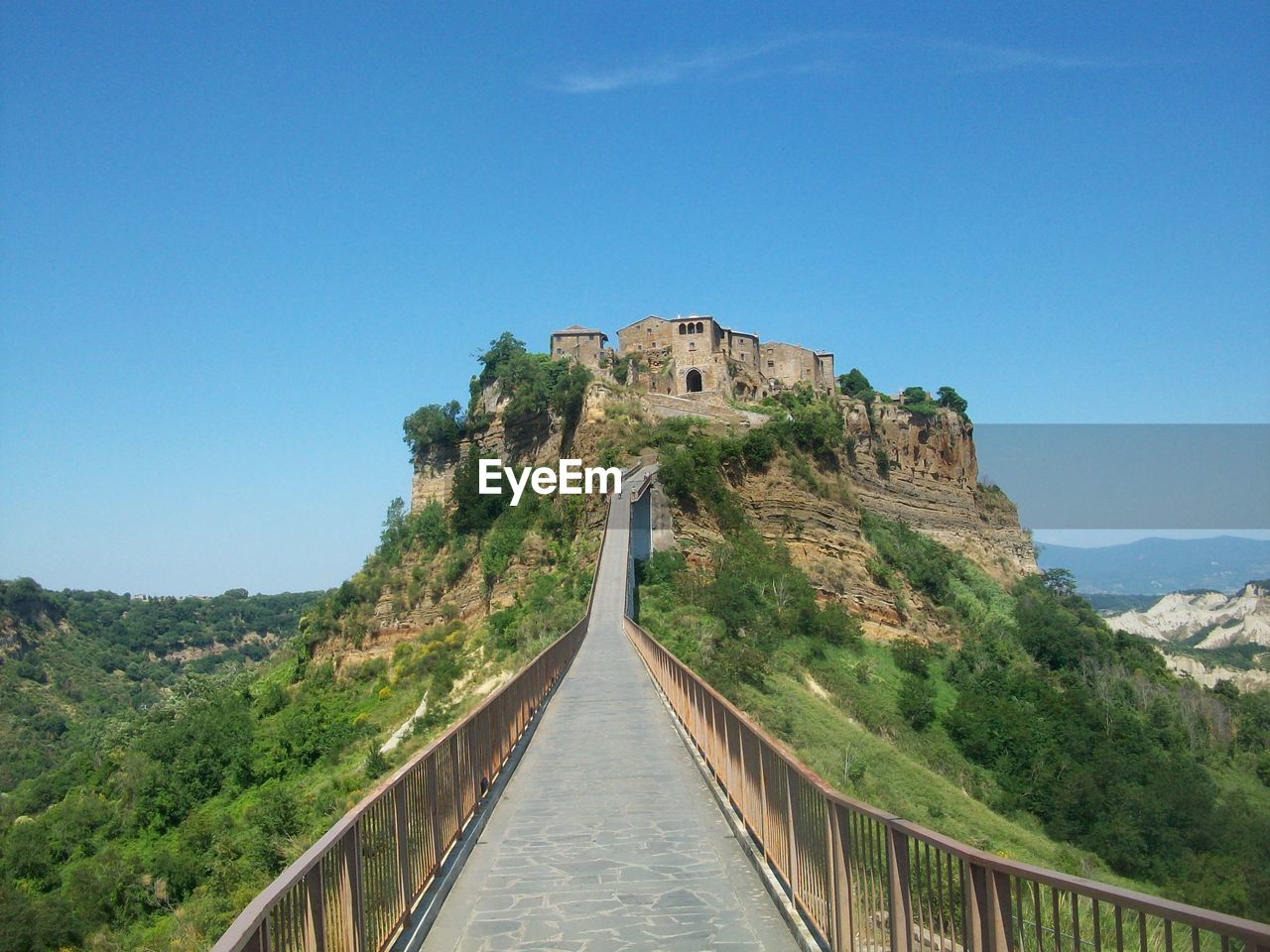 Low angle view of walkway leading towards castle against blue sky