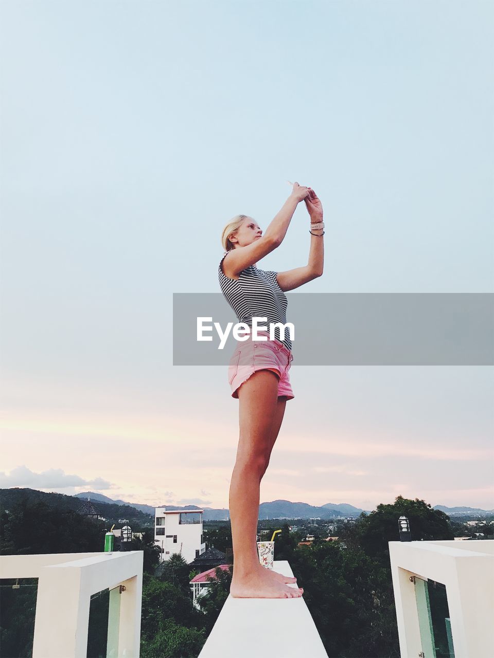 Side view of woman standing against cloudy sky during sunset