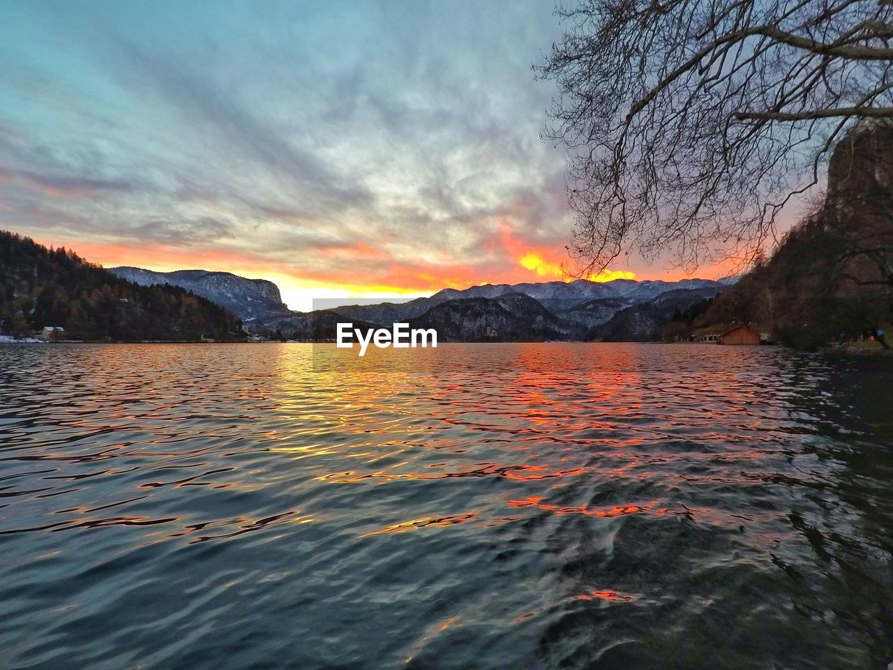 SCENIC VIEW OF LAKE BY MOUNTAINS AGAINST SKY AT SUNSET