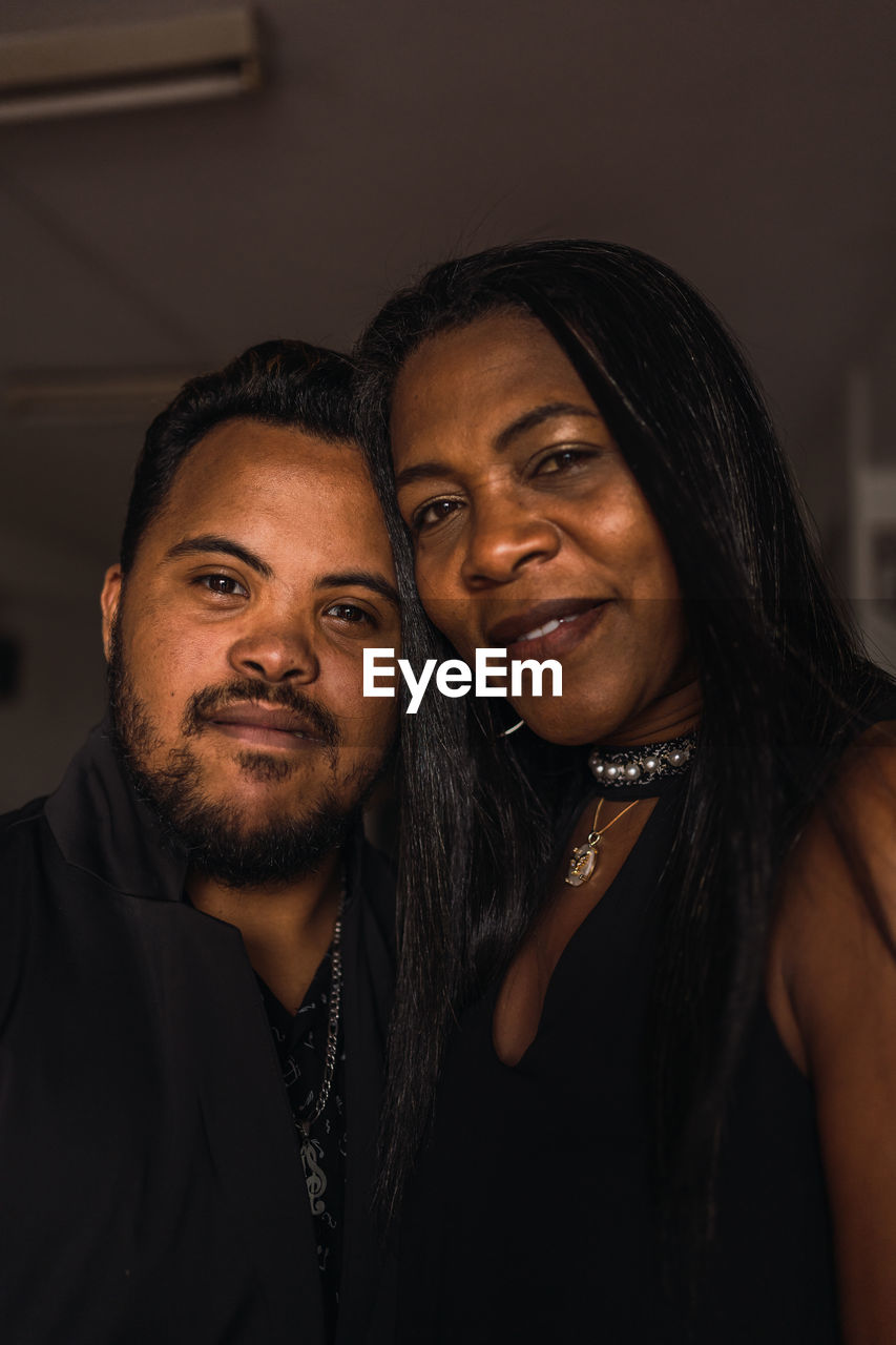 Delighted african american female and male in black clothes standing together and looking at camera