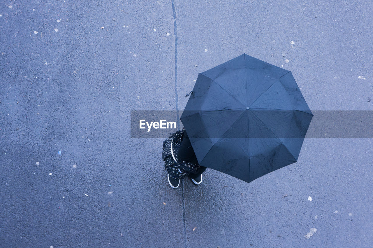 Directly above shot of person standing with umbrella on road during monsoon