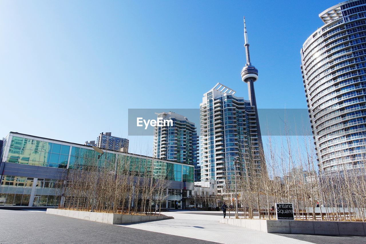 Low angle view of cn tower and buildings against clear sky on sunny day