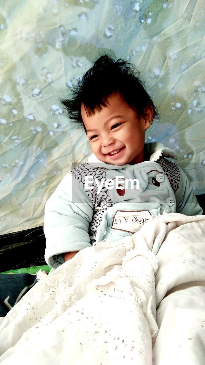 child, one person, childhood, person, men, baby, innocence, high angle view, skin, cute, portrait, toddler, relaxation, babyhood, emotion, happiness, water, smiling, nature, front view, lifestyles, black hair, human face, clothing, bed, eyes closed, indoors, day, baby clothing, three quarter length, casual clothing, leisure activity