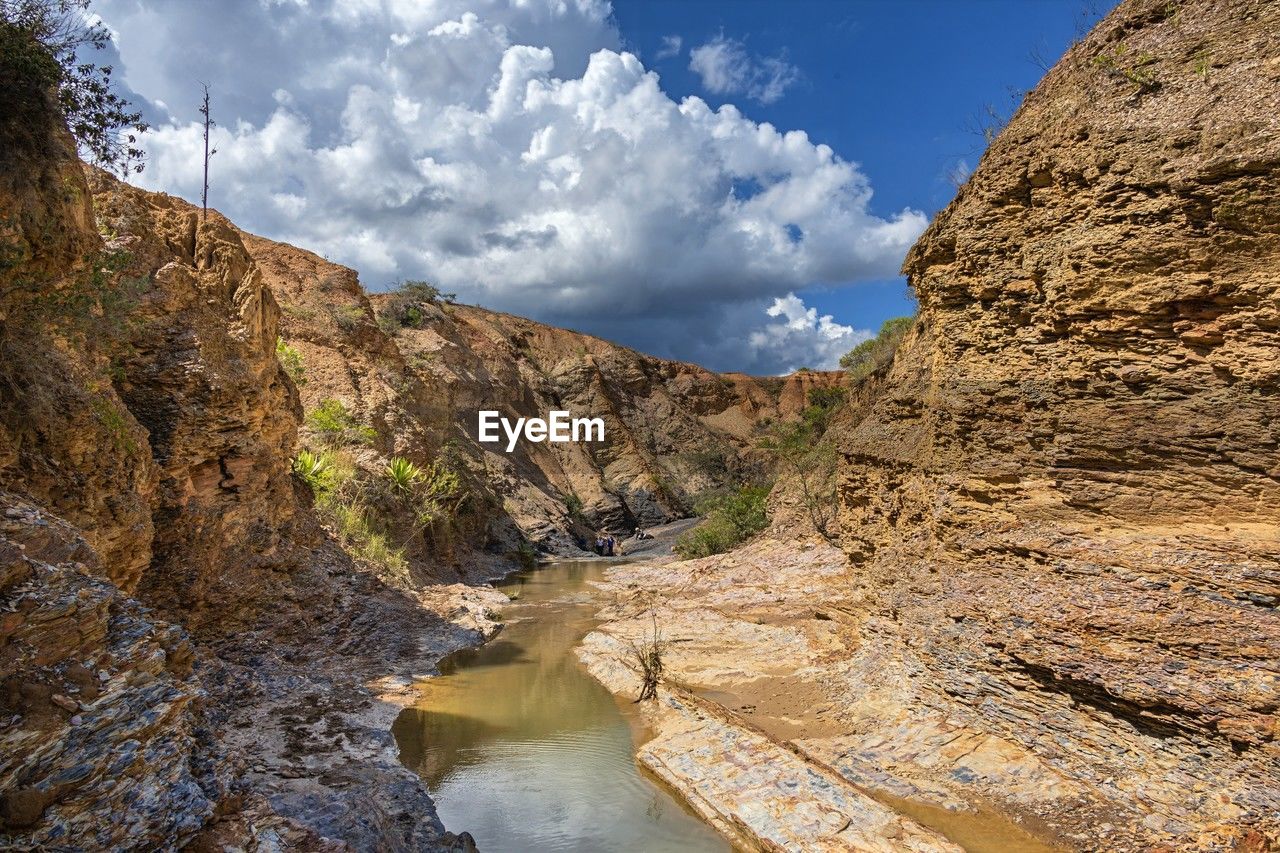 environment, water, landscape, scenics - nature, cloud, sky, nature, beauty in nature, rock, mountain, valley, land, wadi, travel destinations, travel, wilderness, canyon, geology, non-urban scene, no people, river, cliff, mountain range, tourism, rock formation, tranquility, outdoors, blue, activity, plant, terrain, tranquil scene, tree, day, accidents and disasters, extreme terrain, ravine, social issues, outdoor pursuit, idyllic, reflection