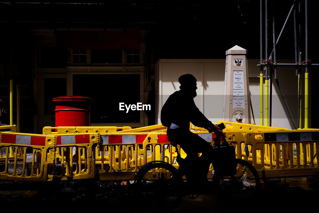 Side view of silhouette man on bike red post box 