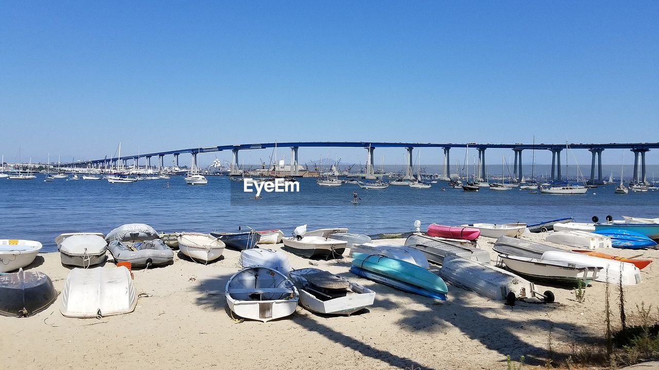 Boats moored in sea against clear blue sky