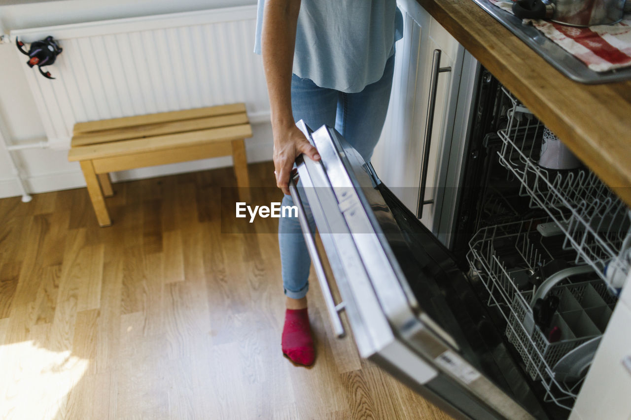 Woman opening dishwasher