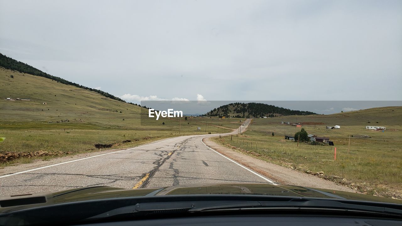 ROAD BY MOUNTAINS SEEN THROUGH CAR WINDSHIELD