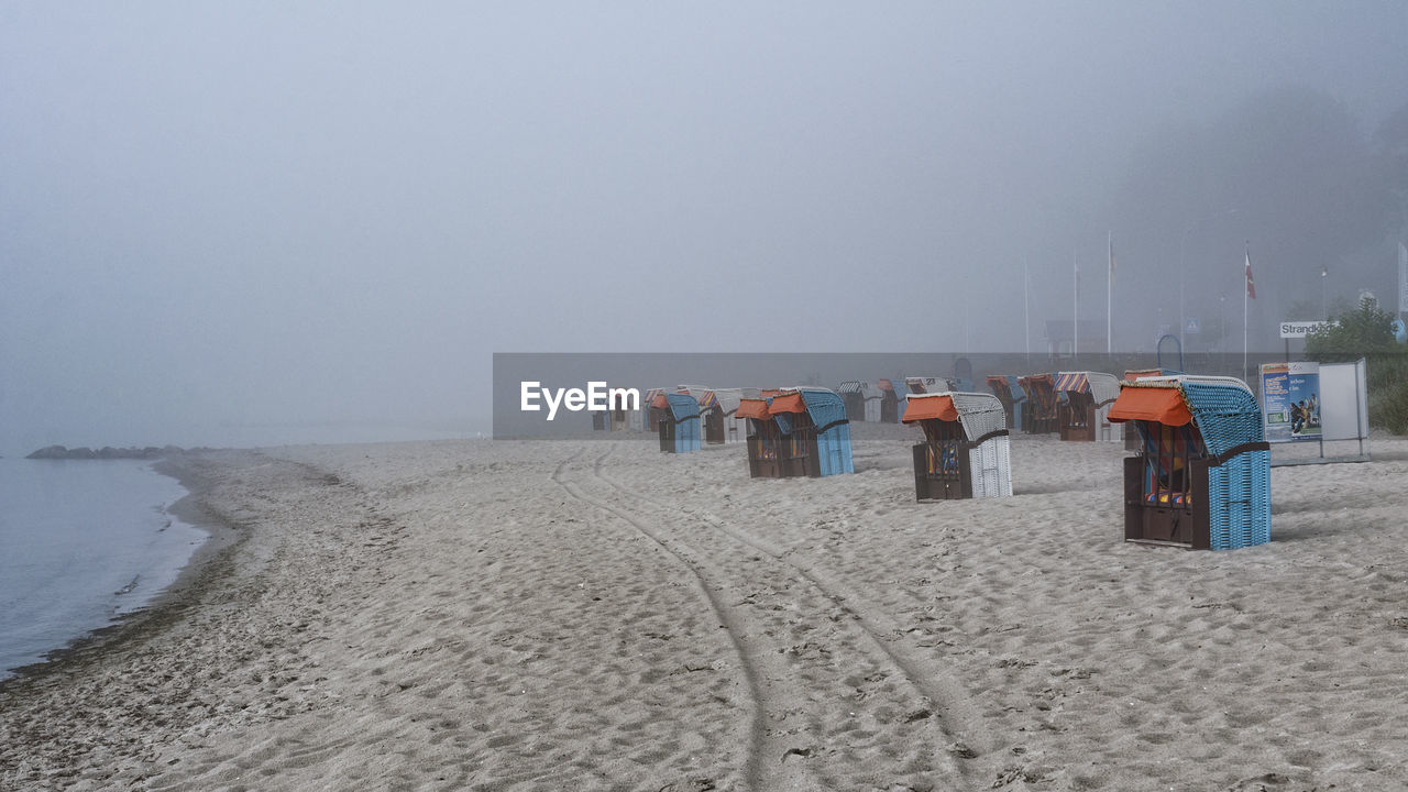 Seats on calm beach against clear sky