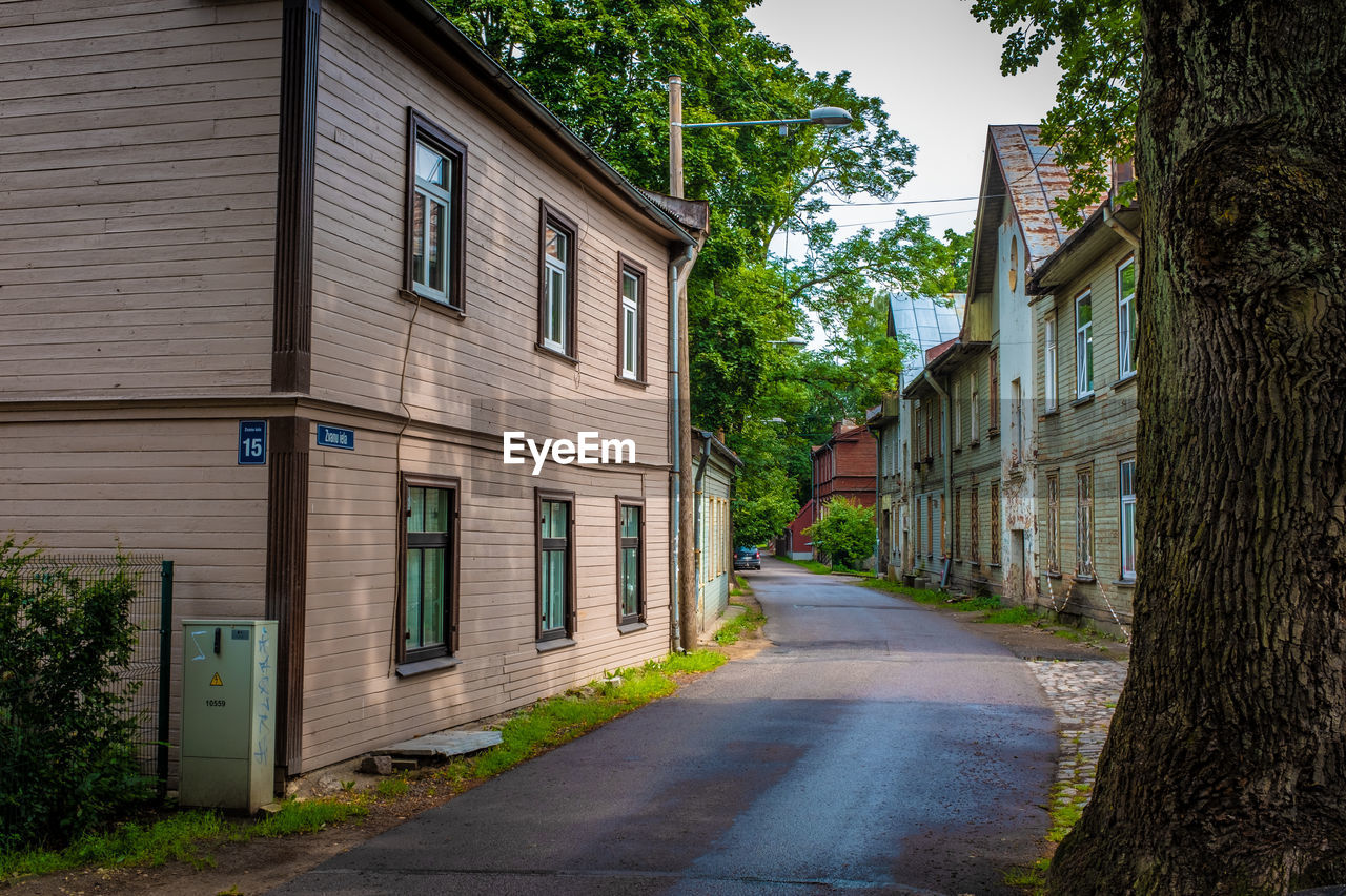 EMPTY ROAD AMIDST BUILDINGS AND TREES