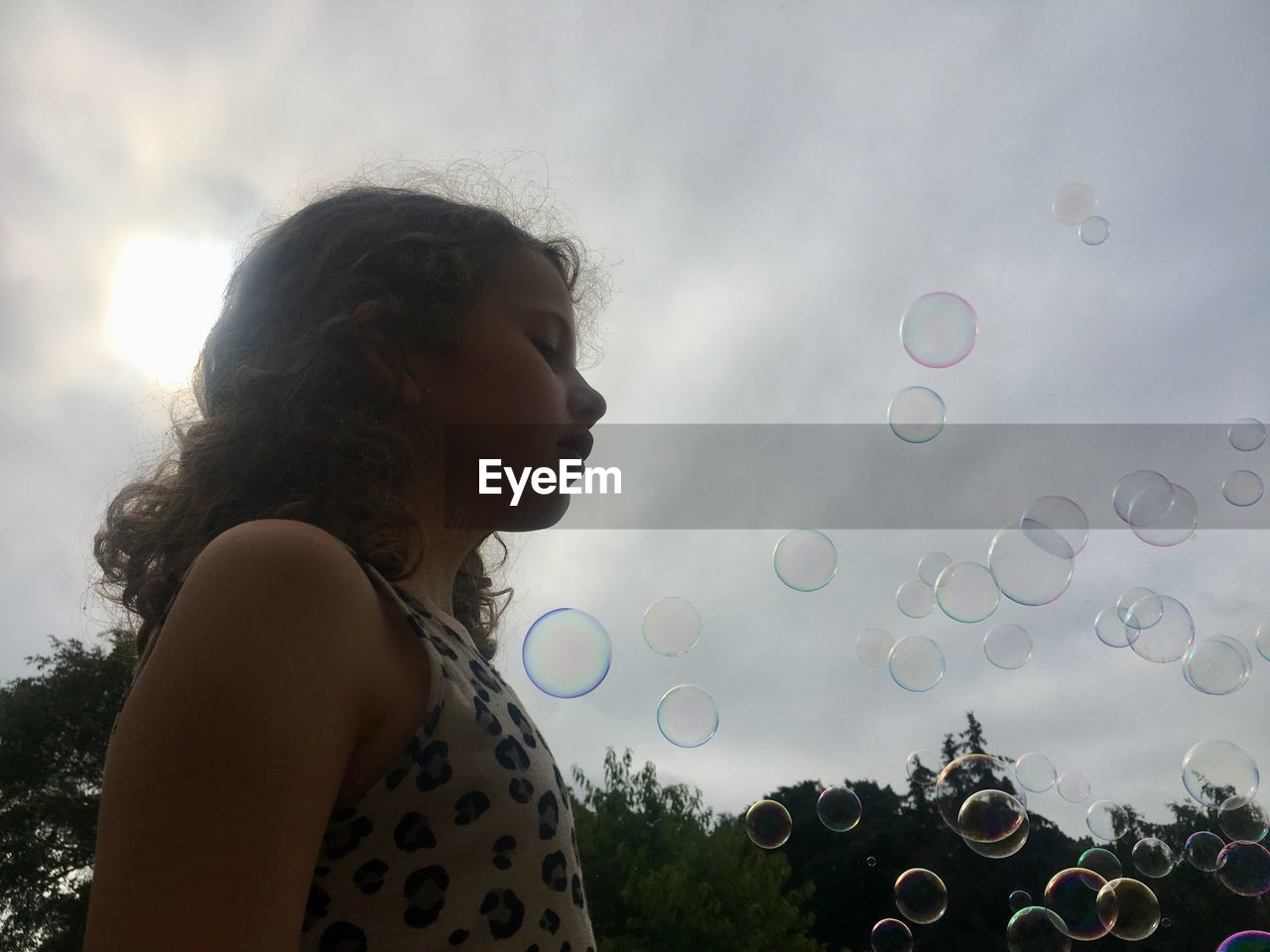 LOW ANGLE VIEW OF WOMAN LOOKING AT BUBBLES