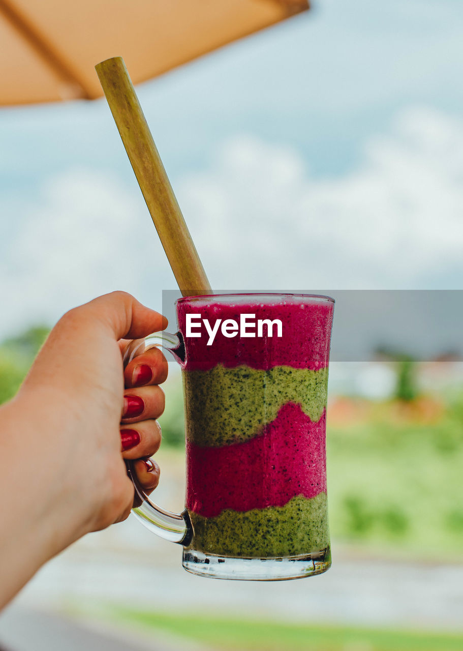 MIDSECTION OF PERSON HOLDING DRINK WITH GLASS OF JUICE